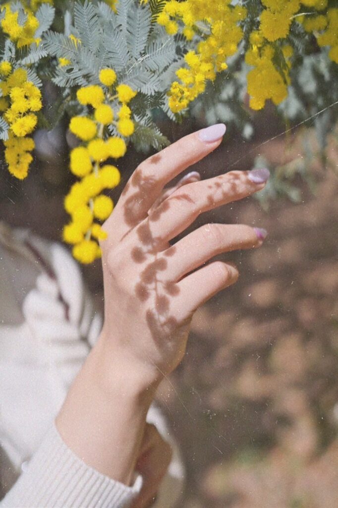 黄色い花とネイルをした女性の手
